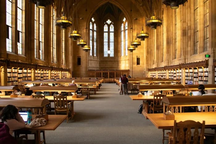 A grand university library reading room with long wooden desks
