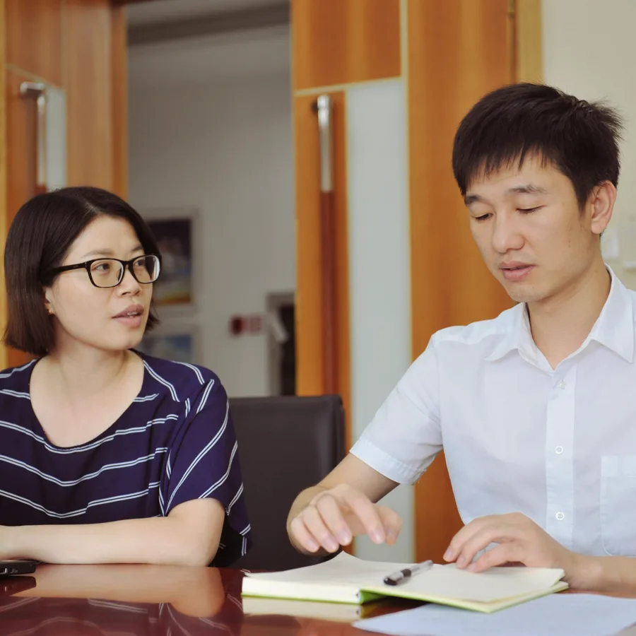 A mentor and a student going through notes together at a table
